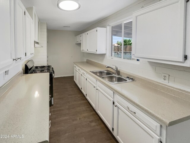 kitchen with white cabinets, stainless steel gas range, decorative backsplash, and a sink