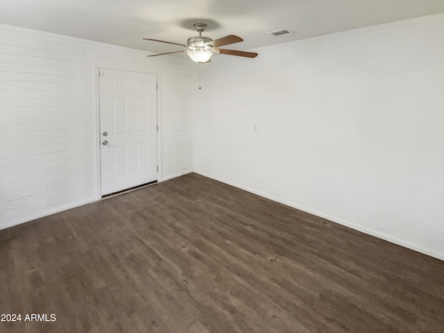 spare room featuring baseboards, a ceiling fan, visible vents, and dark wood finished floors