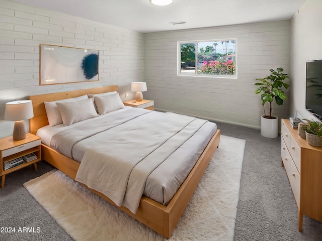 bedroom with light carpet and brick wall