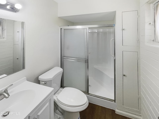 full bathroom with toilet, wood finished floors, vanity, and a stall shower