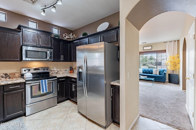 13318 W Indianola Ave, Litchfield Park, AZ 85340 - kitchen featuring stainless steel appliances, arched walkways, light stone countertops, light tile patterned floors, and light colored carpet
