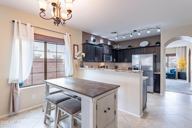 13318 W Indianola Ave, Litchfield Park, AZ 85340 - kitchen with stainless steel appliances, arched walkways, a chandelier, and light tile patterned floors