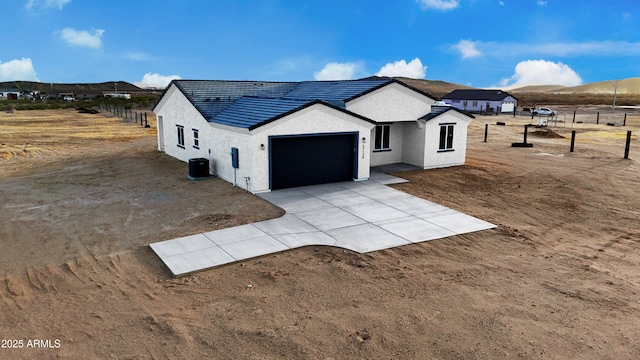 modern inspired farmhouse with central AC, an attached garage, driveway, and stucco siding