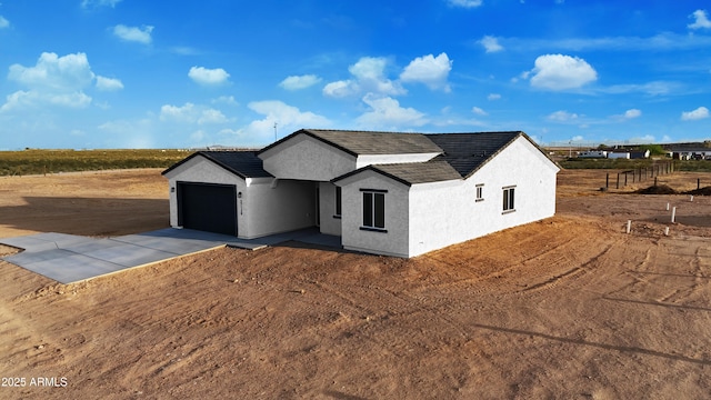 view of front of home featuring stucco siding, a garage, and driveway