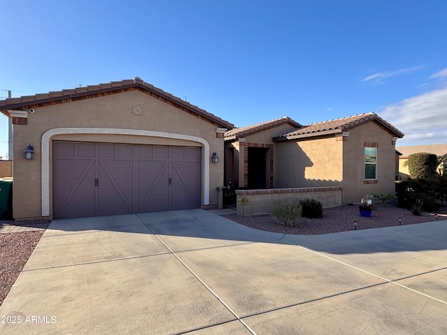 mediterranean / spanish-style home with stucco siding, driveway, a tile roof, and a garage