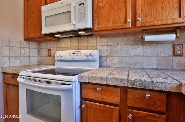 kitchen with white appliances, brown cabinets, tile counters, and tasteful backsplash