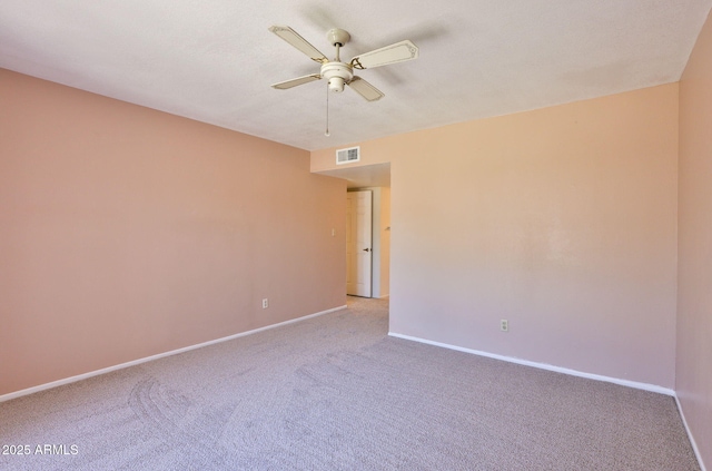 spare room with baseboards, ceiling fan, light colored carpet, and visible vents