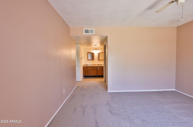 empty room with light colored carpet, ceiling fan, visible vents, and baseboards