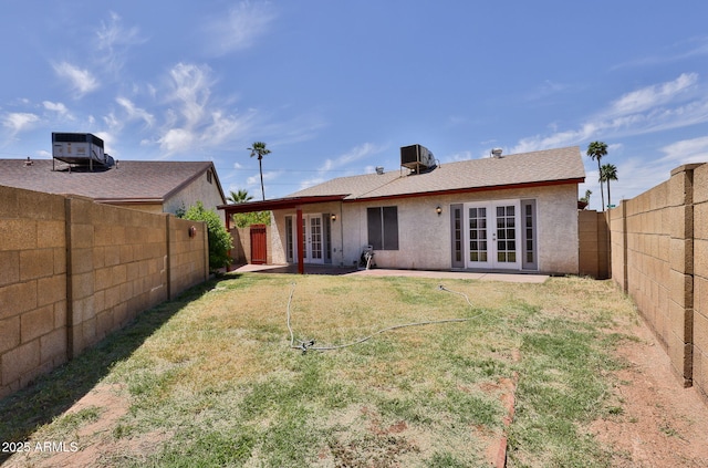 back of property with a yard, central AC, french doors, and a fenced backyard