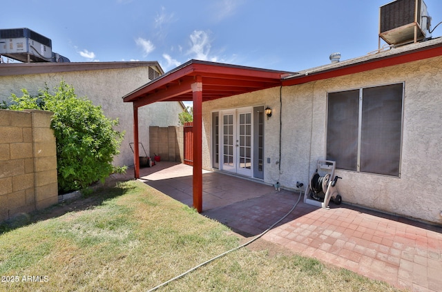 back of house with stucco siding, cooling unit, a patio area, french doors, and a yard