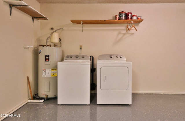 clothes washing area featuring baseboards, washing machine and dryer, and electric water heater