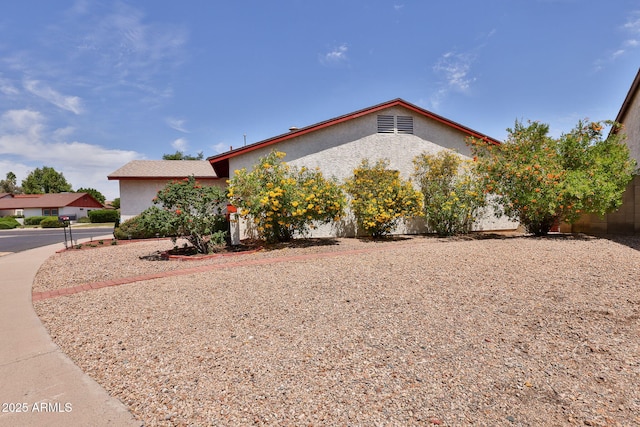 view of side of home with stucco siding and fence