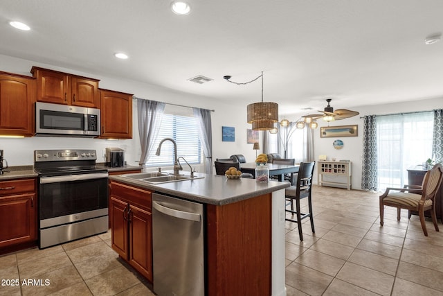 kitchen featuring pendant lighting, sink, a kitchen island with sink, stainless steel appliances, and light tile patterned flooring