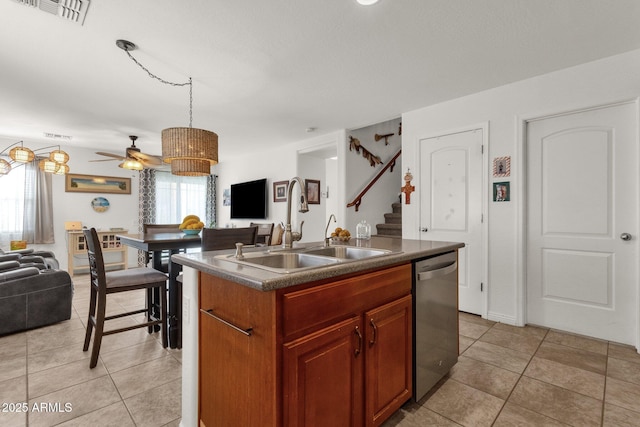 kitchen with decorative light fixtures, sink, a kitchen island with sink, stainless steel dishwasher, and light tile patterned floors