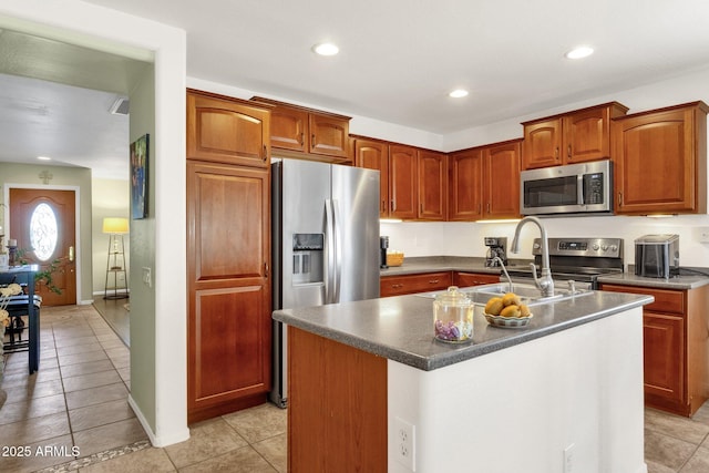 kitchen with appliances with stainless steel finishes, sink, a center island with sink, and light tile patterned floors