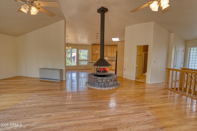 unfurnished living room with a wood stove, a ceiling fan, and lofted ceiling