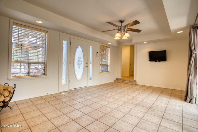 entrance foyer with light tile patterned floors, a ceiling fan, recessed lighting, a raised ceiling, and baseboards