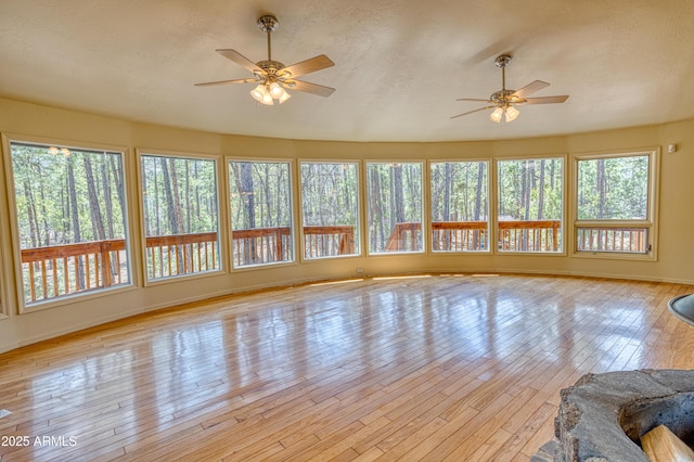 unfurnished sunroom featuring baseboards, hardwood / wood-style floors, and a textured ceiling