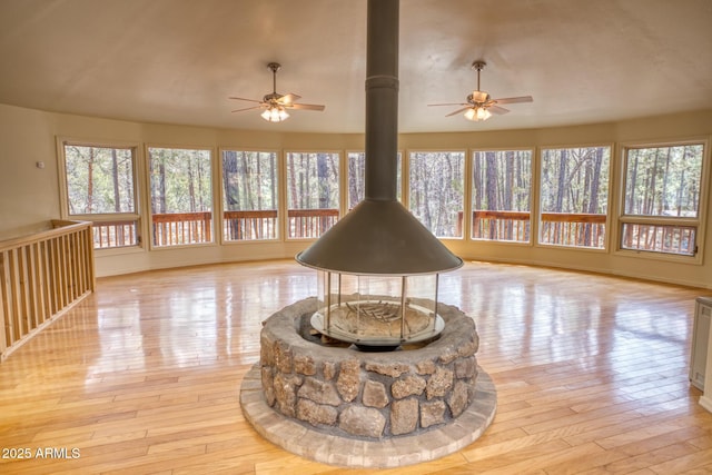 interior space featuring light wood-type flooring, a wood stove, and a ceiling fan