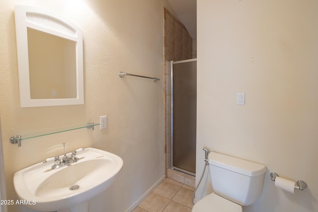 full bath featuring toilet, a stall shower, a sink, and tile patterned floors