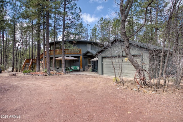 view of front of home with a wooden deck, a garage, driveway, and stairs