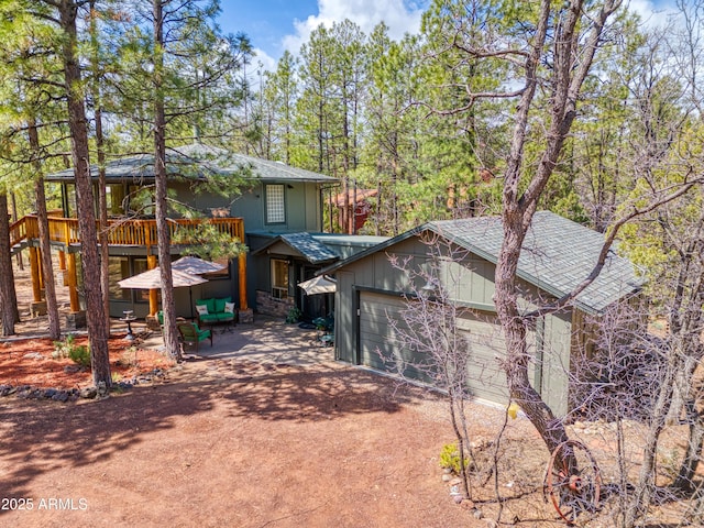 exterior space featuring an attached garage, a patio, roof with shingles, and dirt driveway