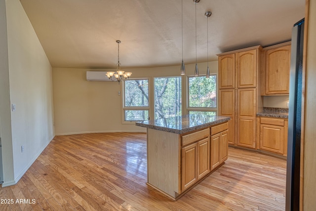 kitchen with a chandelier, a kitchen island, light wood-style flooring, and dark countertops
