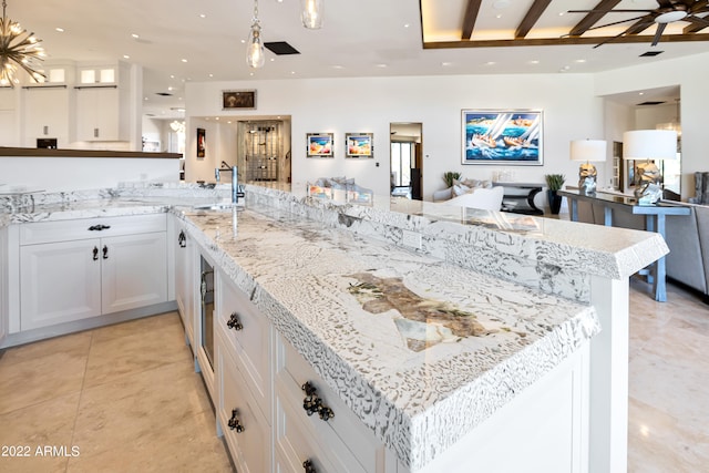 kitchen with ceiling fan, white cabinetry, light tile floors, and light stone counters