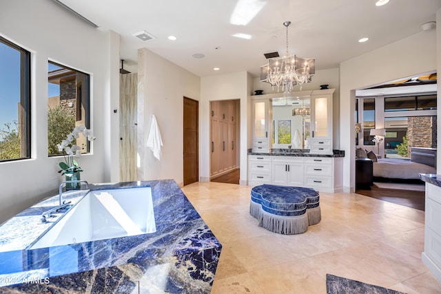 bathroom featuring an inviting chandelier, tile floors, vanity, and a bath to relax in