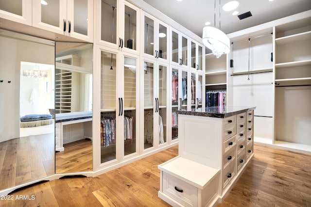 walk in closet featuring an inviting chandelier and light wood-type flooring