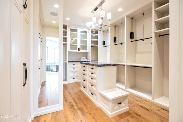 spacious closet with an inviting chandelier and light hardwood / wood-style flooring