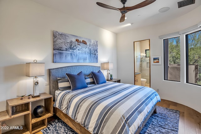 bedroom featuring dark hardwood / wood-style flooring, ceiling fan, and connected bathroom