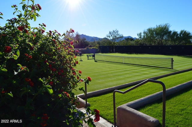 view of tennis court featuring a mountain view and a lawn