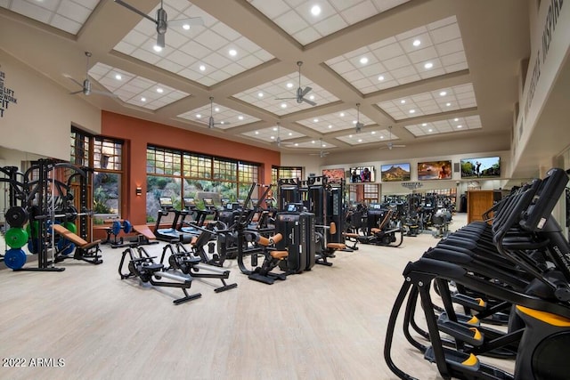 workout area with coffered ceiling, ceiling fan, light hardwood / wood-style floors, and a high ceiling