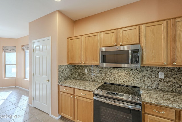 kitchen featuring backsplash, light stone countertops, stainless steel appliances, and light tile patterned floors