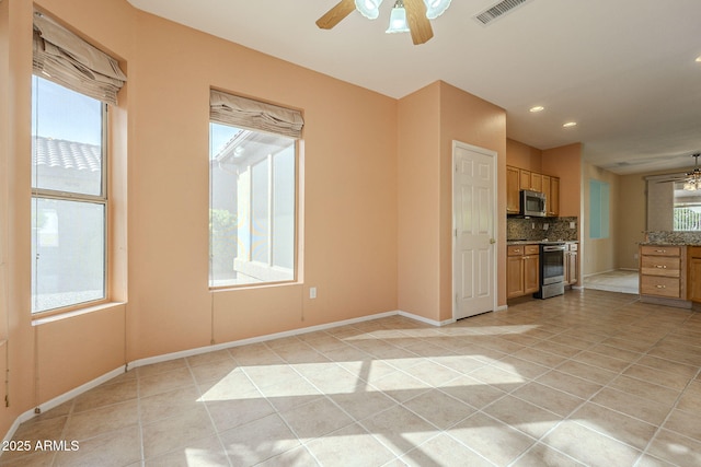 kitchen featuring tasteful backsplash, a wealth of natural light, light tile patterned floors, and stainless steel appliances