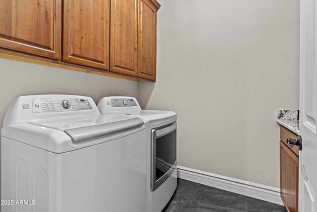 washroom featuring cabinets, separate washer and dryer, and dark tile patterned flooring