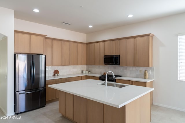 kitchen featuring stainless steel fridge, sink, a center island with sink, light brown cabinetry, and decorative backsplash