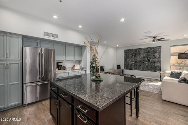 kitchen featuring a kitchen bar, visible vents, wood finished floors, open floor plan, and freestanding refrigerator