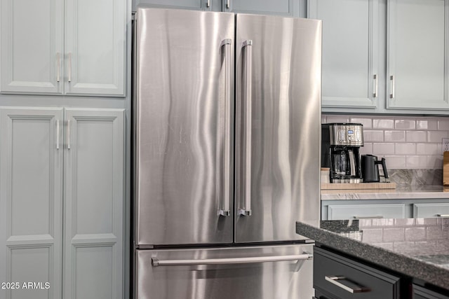 kitchen featuring decorative backsplash, high quality fridge, and dark stone counters