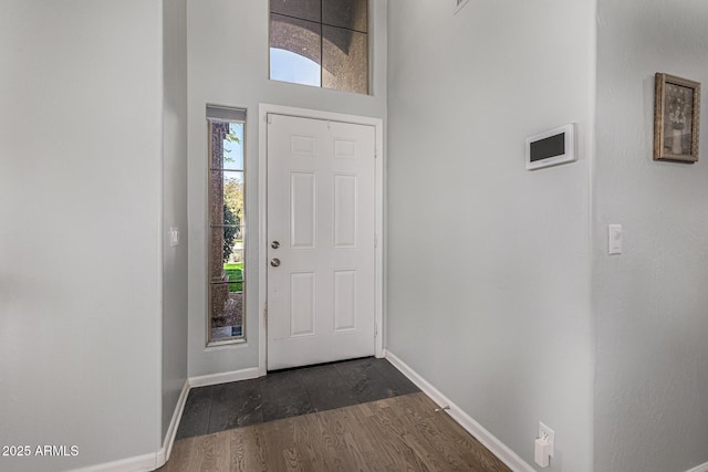 entrance foyer featuring dark wood-type flooring, baseboards, and a towering ceiling