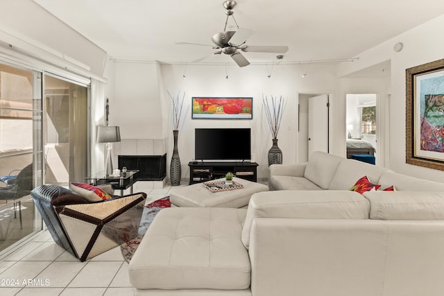 living room with a tiled fireplace, light tile patterned floors, and ceiling fan