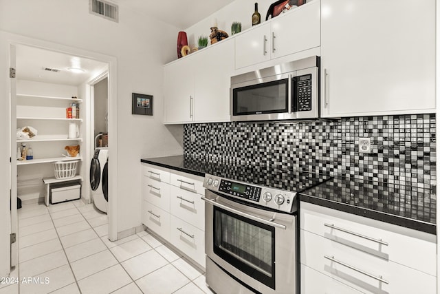 kitchen with visible vents, white cabinetry, appliances with stainless steel finishes, washer and dryer, and dark countertops