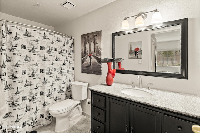 bathroom with visible vents, toilet, vanity, and a textured wall