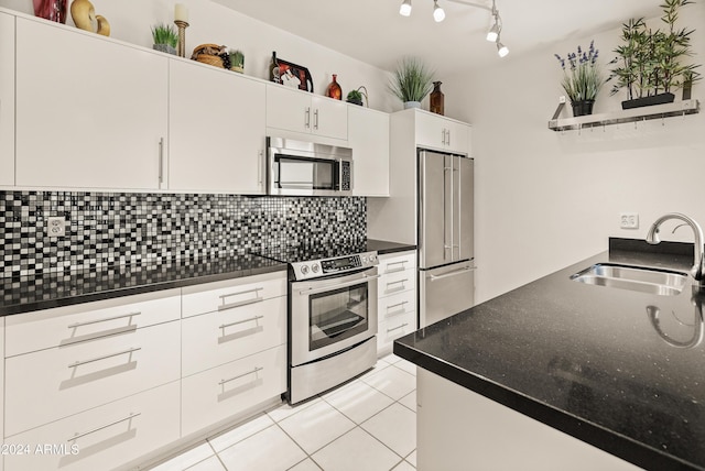 kitchen with a sink, dark countertops, appliances with stainless steel finishes, light tile patterned floors, and decorative backsplash