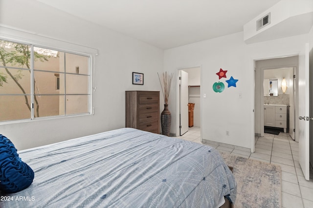 bedroom featuring light tile patterned floors, visible vents, a walk in closet, and ensuite bathroom