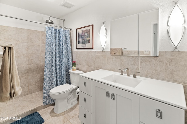 bathroom featuring visible vents, toilet, vanity, tiled shower, and tile walls