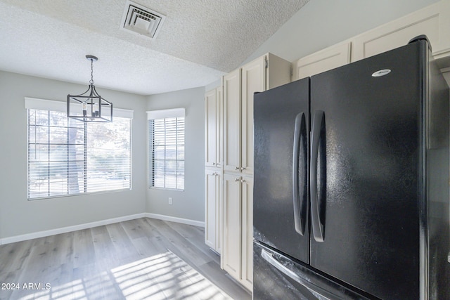 kitchen featuring pendant lighting, black fridge, a textured ceiling, a notable chandelier, and light hardwood / wood-style floors