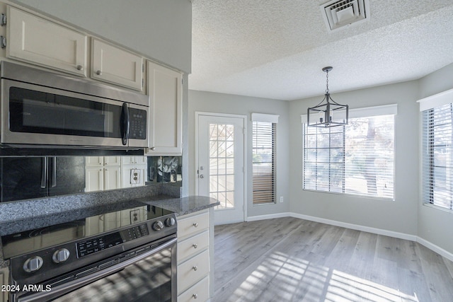 kitchen with white cabinetry, pendant lighting, stainless steel appliances, and light hardwood / wood-style flooring