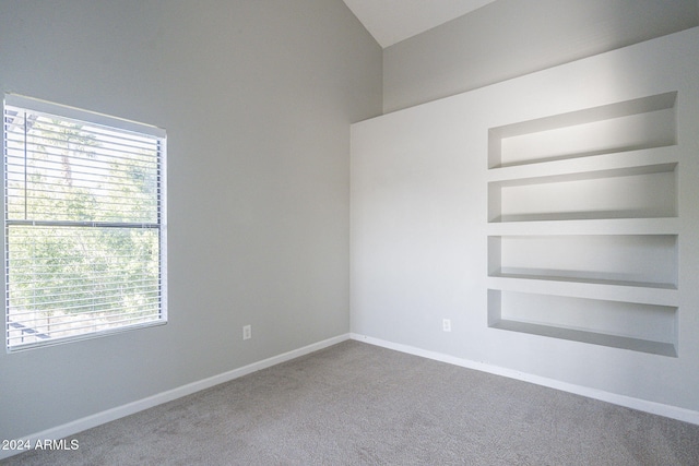 unfurnished room featuring carpet, built in shelves, and lofted ceiling